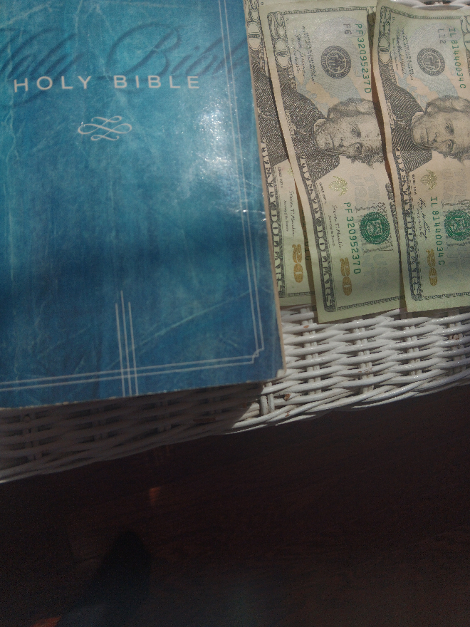 money and the Bible on a bedside table money and the Bible on a bedside table