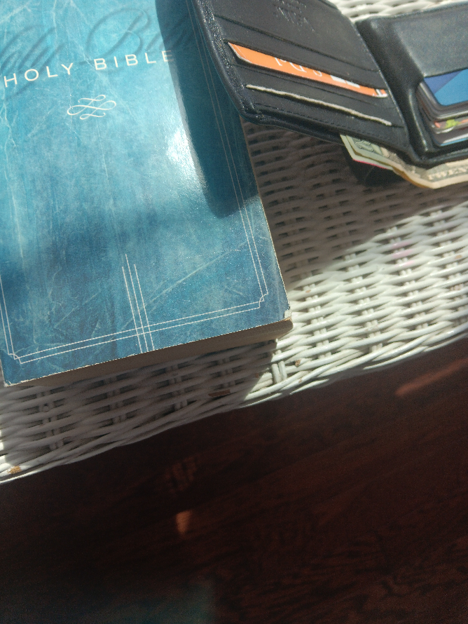 wallet and the Bible on a bedside table wallet and the Bible on a bedside table